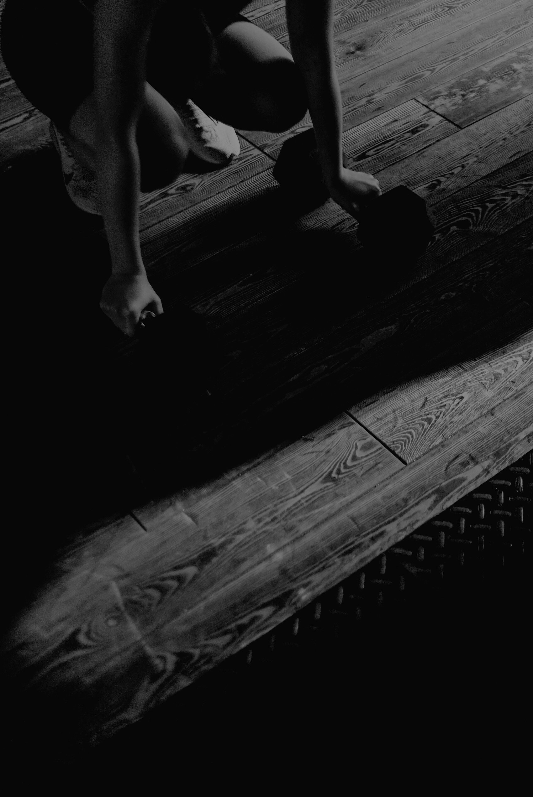 Person in White Shorts and Black Shoes Standing on Brown Wooden Floor